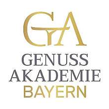 Logo mit großem G, stilisiert durch Arm und Serviertablett, und großem A, darunter Schriftzug „Genussakademie“.